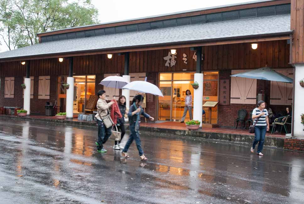雨天的木造建築與撐傘的遊客